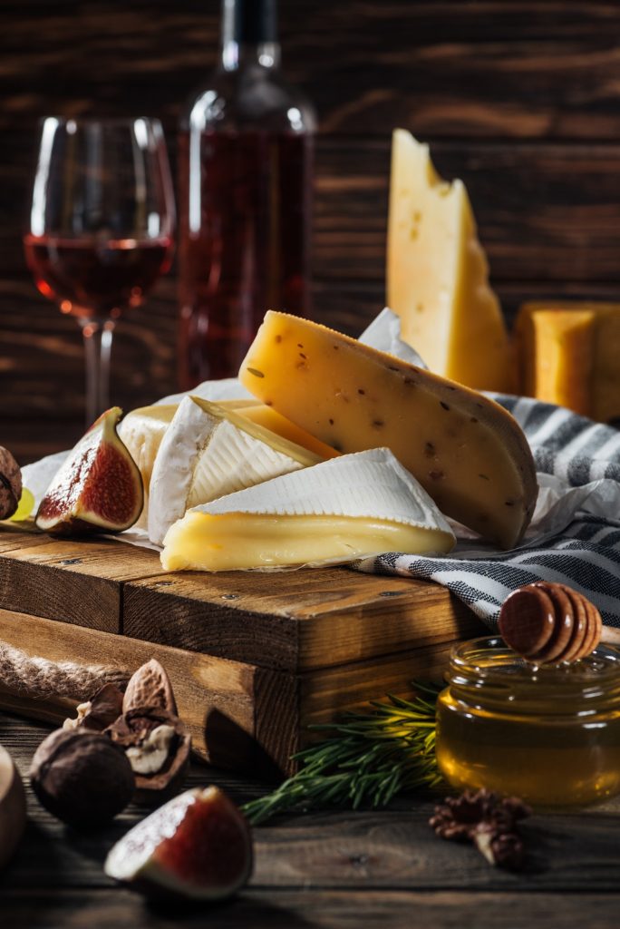 different types of cheeses, honey and walnuts on table